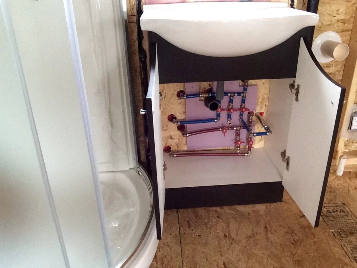 PEX manifold with brass fittings and individual shutoff valves inside the bathroom vanity