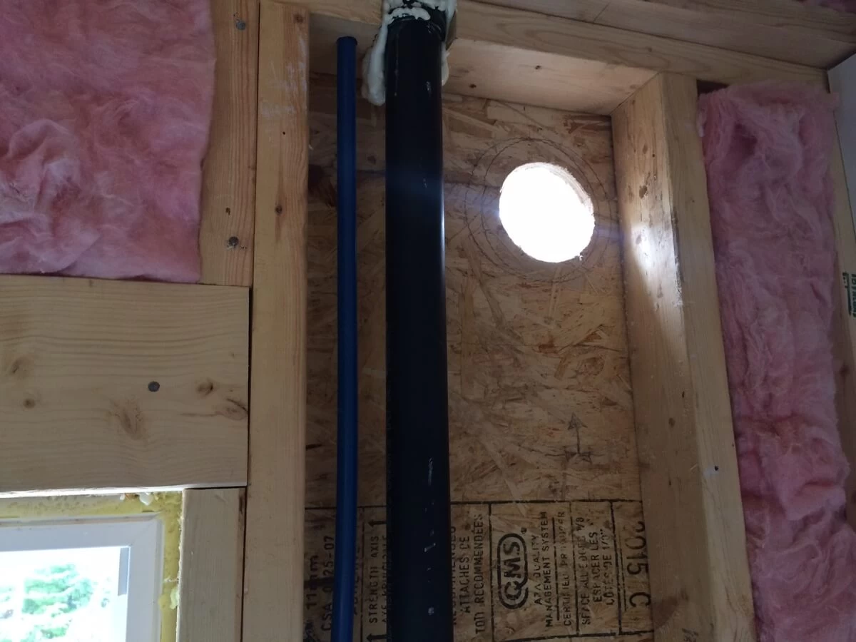 Circular wall opening beside plumbing and framing during the 2016 bathroom build