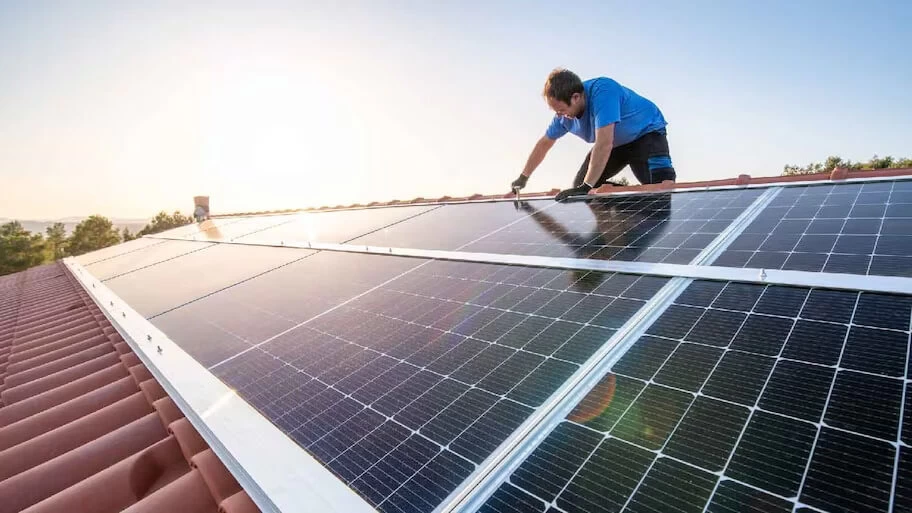 Image of man on the roof inspecting solar panels after cleaning them